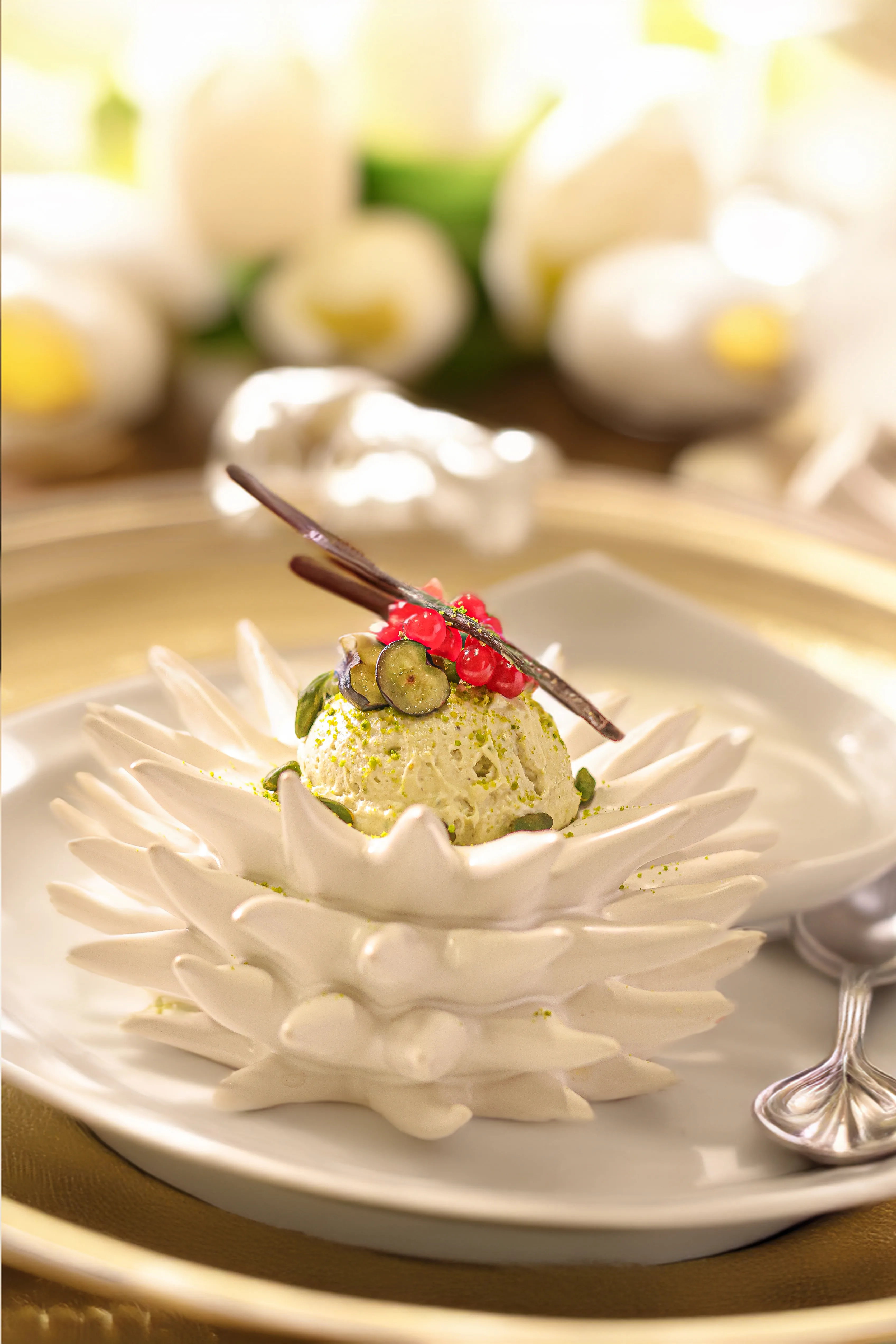 Bellucci Berlin – Pistazien-Mousse auf kunstvollem Porzellanteller mit goldener Tischdekoration
